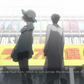Mayuri and Okabe standing in front of a store with a large sign.